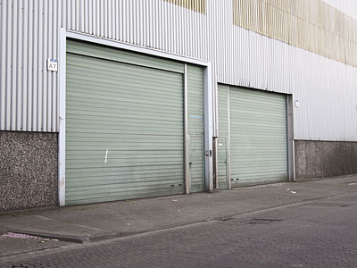 Zwei graue Rolltore an einer Industriegebäude-Fassade.